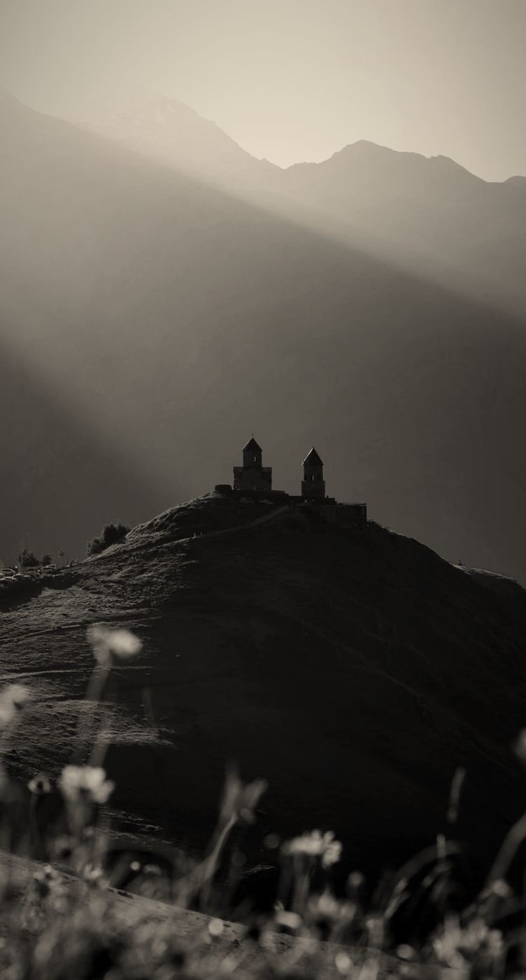 Gergeti Trinity Church silhouetted on its hill below the mountains